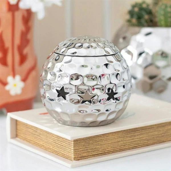 Silver disco ball oil burner with star-shaped cutouts and mirrored finish
