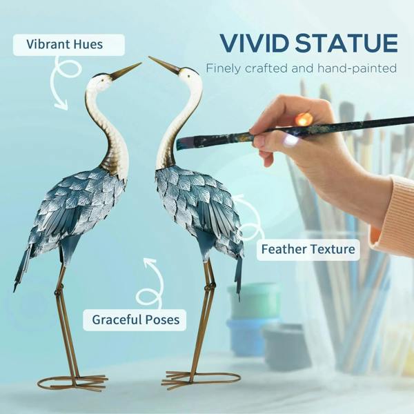 Steel crane ornaments with white heads and blue feather patterns, shown during hand painting