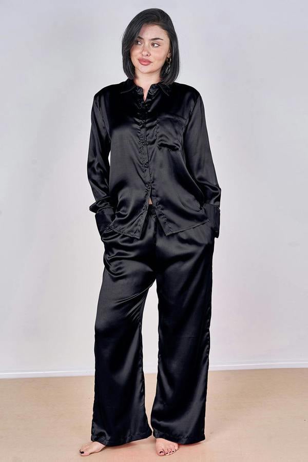 Person wearing a black satin pajama set against a plain background