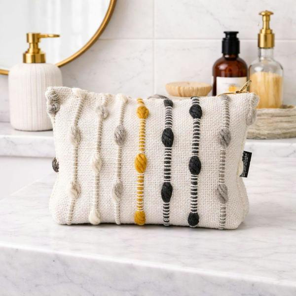 Nomad Sari jacquard toiletry bag in cream with yellow, black, and gray vertical stripe trim.