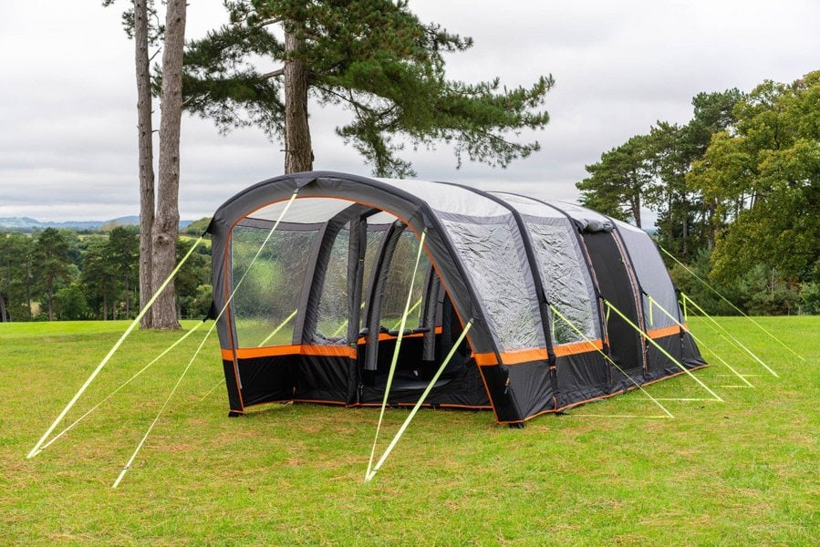 An image of the OLPRO Blakedown Breeze 4 Berth Inflatable Tent pitched on a campsite with a treeline in the background.