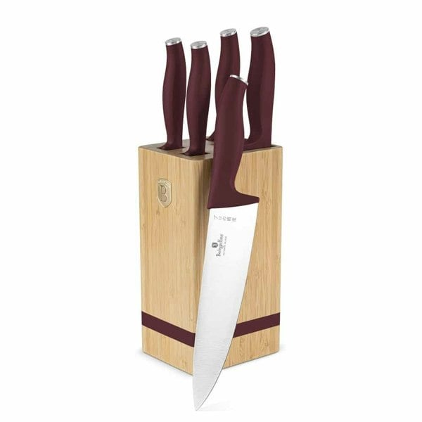 Five knives with Bordeaux handles and stainless steel blades stored in a light brown bamboo knife block. One chef's knife leans against the block.