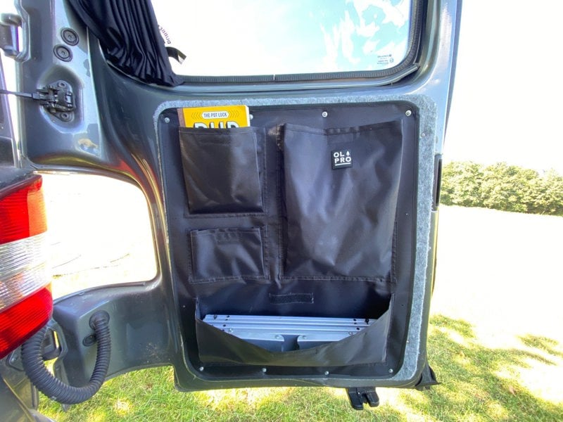 An image of the right hand side of the VW T5/T6 Barn Door Storage Organiser with some items stowed inside of it.