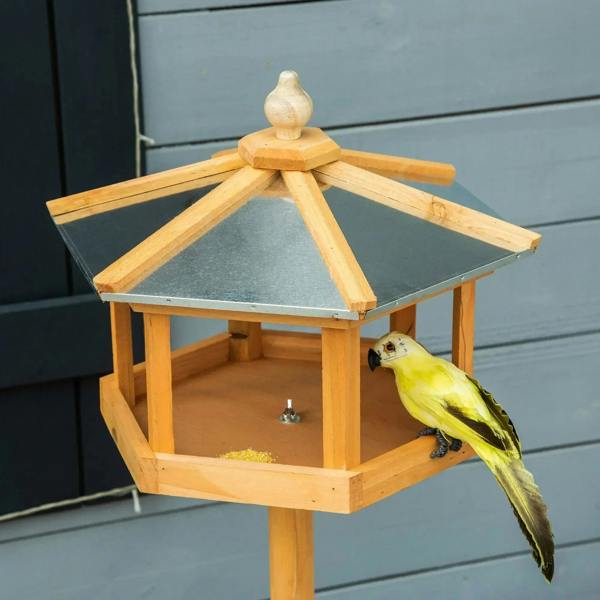 Wooden bird feeder gazebo with open tray and side roof panels, with perched yellow bird