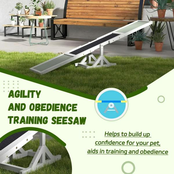 White wooden agility seesaw with black anti-slip ramp and X-frame support on grass