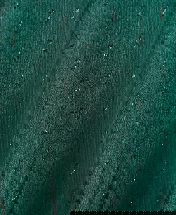 Close-up of a textured green fabric with small black patterns