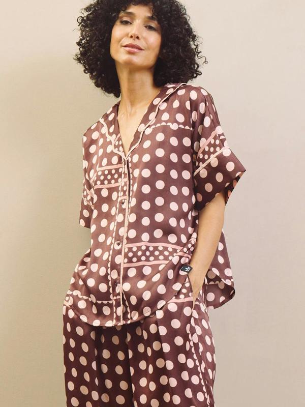 Woman wearing a brown polka dot pyjama set against a beige background