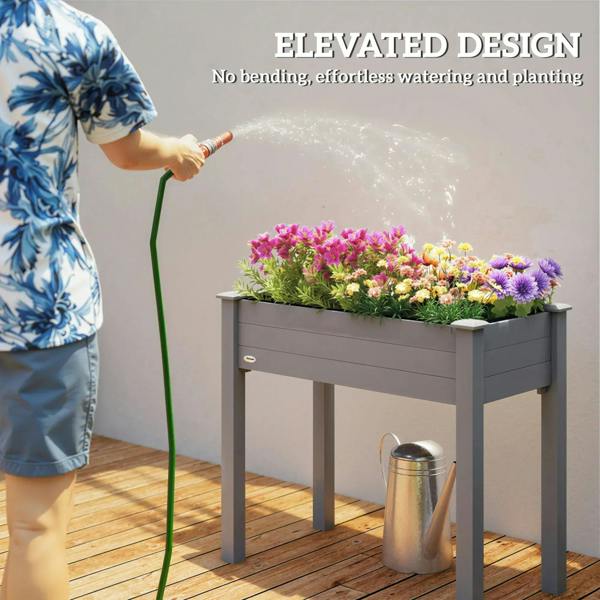 Dark grey raised planter box with colorful flowers, shown being watered on a patio.