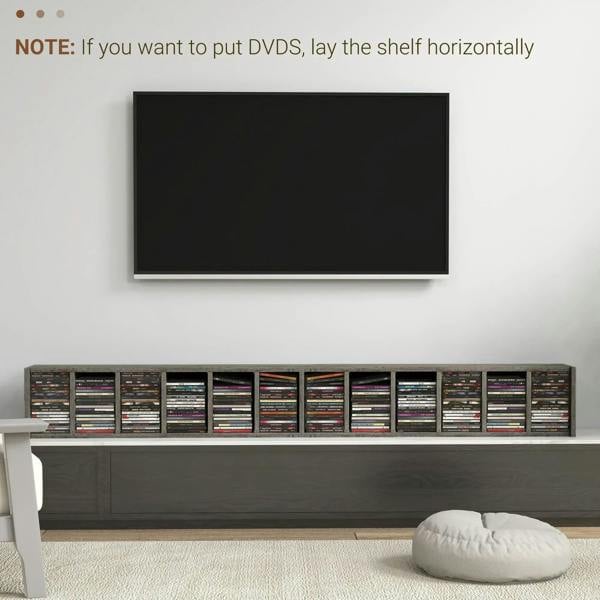 Dark wood-effect CD storage unit on the floor beneath a wall-mounted screen.