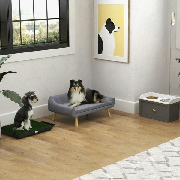 Grey raised dog feeding station with two stainless steel bowls and storage drawer near dogs.