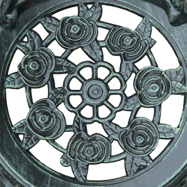 Close-up of antique green cast aluminum tabletop with floral wheel medallion pattern.