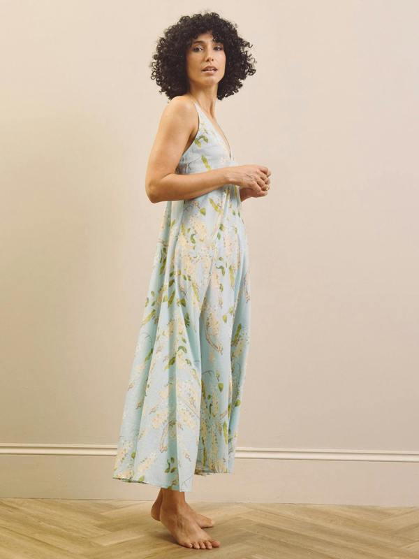 Woman wearing a floral night dress standing against a plain background