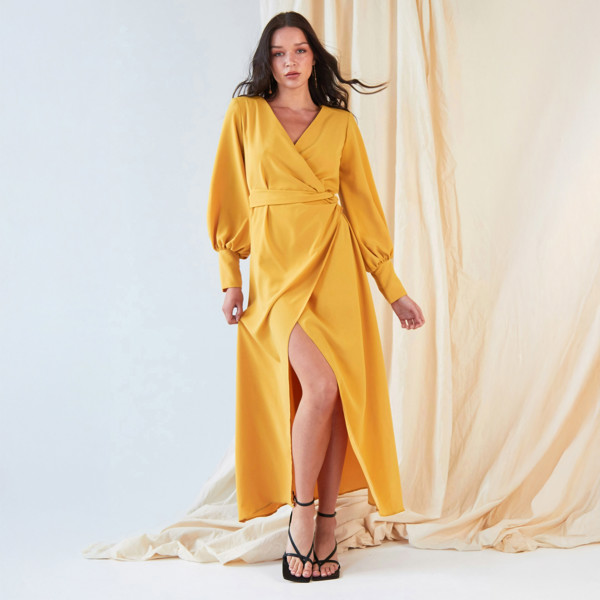 The model is wearing a Sarvin Mustard Wrap Dress with slits.