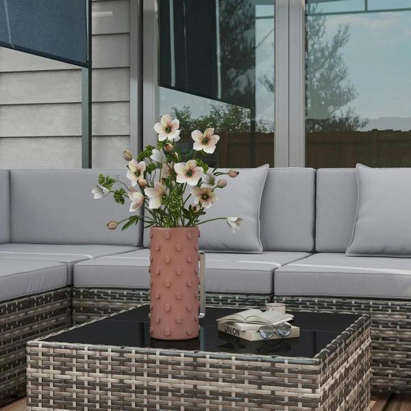 Grey cushion rattan corner sofa set with glass-top coffee table and flower vase.