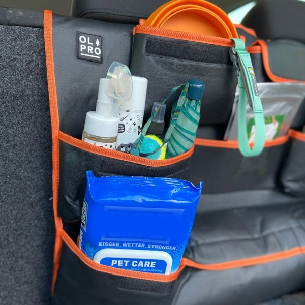 The OLPRO Rear Double Seat Storage Organiser in orange that is full of dog walking items and attached to the back of the rear seats of a VW vehicle.