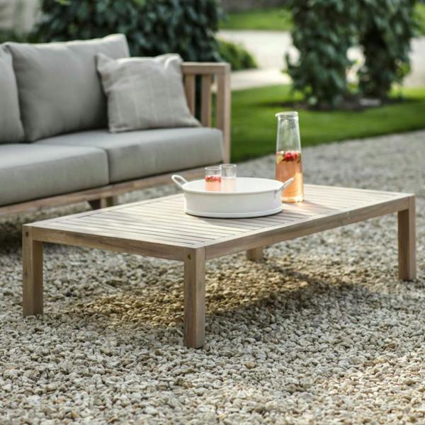 Rectangular whitewash acacia wood coffee table styled with summer drinks on a gravel patio.