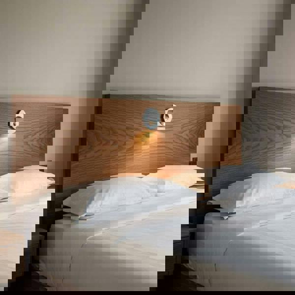 silver recessed wall or headboard reading light mounted in a wooden headboard above a bed