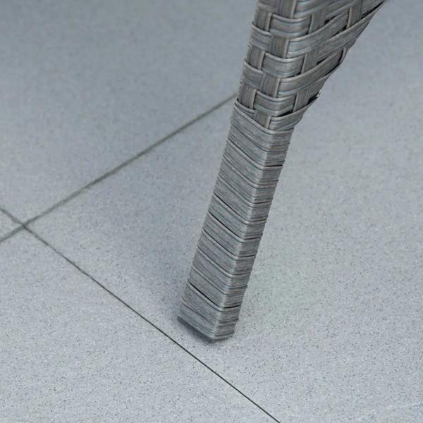 Close-up of grey rattan leg on outdoor tile floor