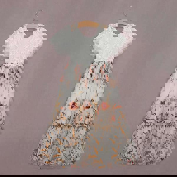 Two-tone dress with white lace top and floral skirt on a hanger against a purple background