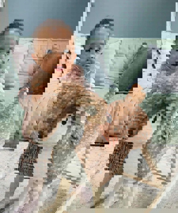 Baby girl wearing pink outfit standing next to Willow Rocking Animal for 1 year old 