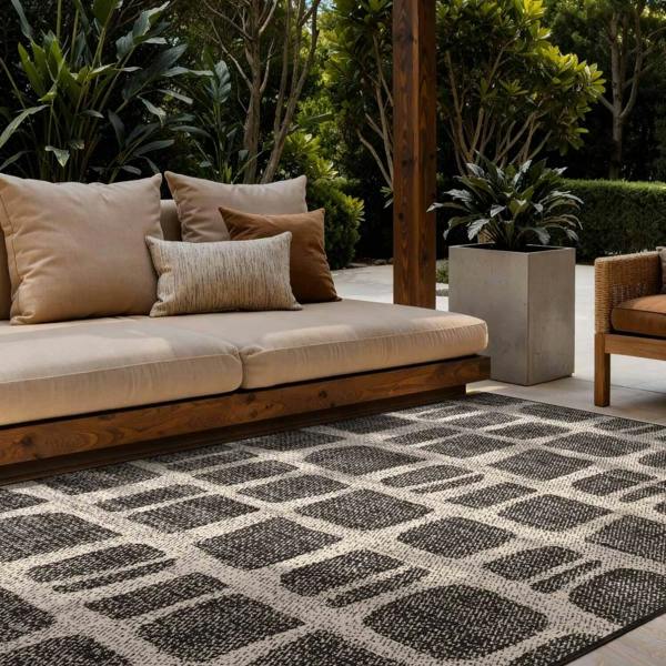 Outdoor seating area with a patterned rug, cushions, and plants.