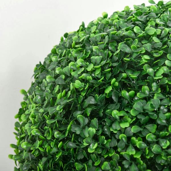 Close-up of green artificial boxwood leaves on a round topiary ball