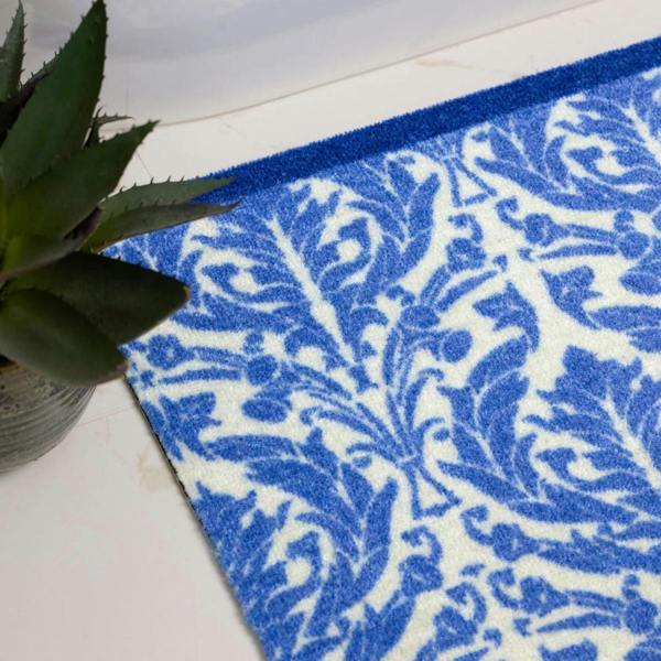 Blue and white patterned rug on a white floor with a plant in the corner.