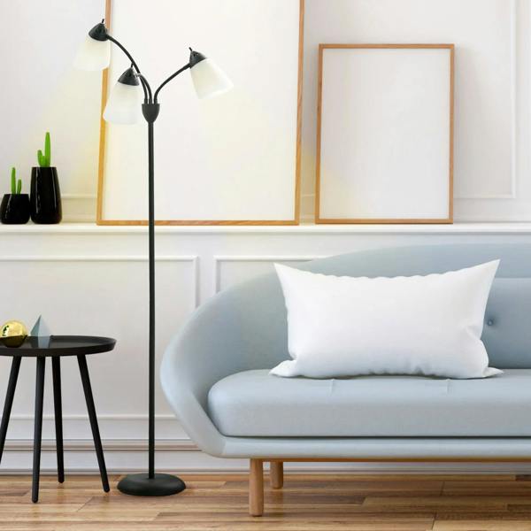 Black standing floor lamp with three adjustable rotating heads and white shades in living room