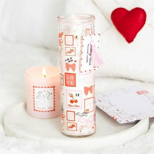Valentine tube candle with clear glass, pink-orange stamp print, tassel, and flame
