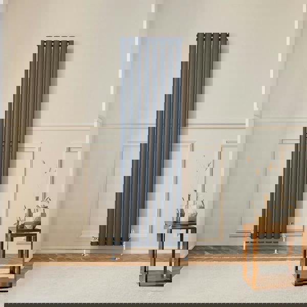 Oval single column radiator in anthracite grey, 1600 x 480mm, mounted on a wall in a modern room with wooden flooring and decor