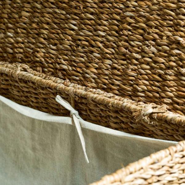 Close-up view of the natural woven seagrass knot detail and removable cream cotton fabric liner on the laundry basket.