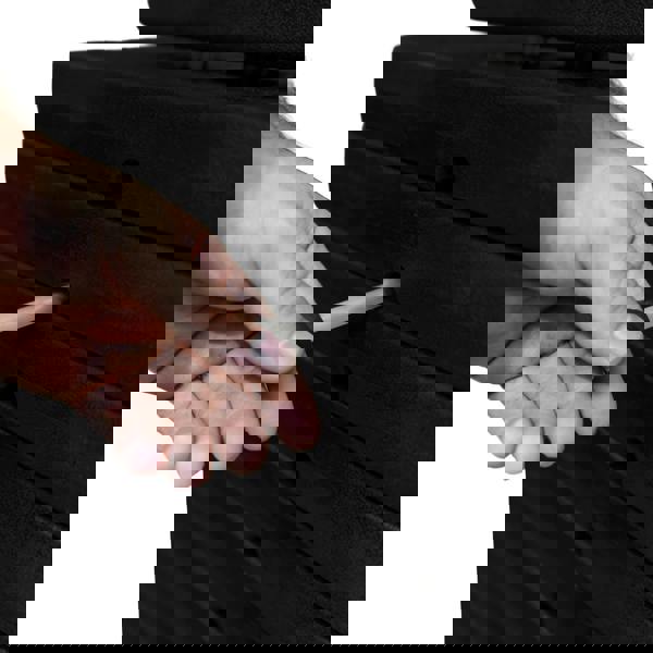 Hand adjusting the weight pin on a stack of black weight plates for a wall-mounted cable pulley machine