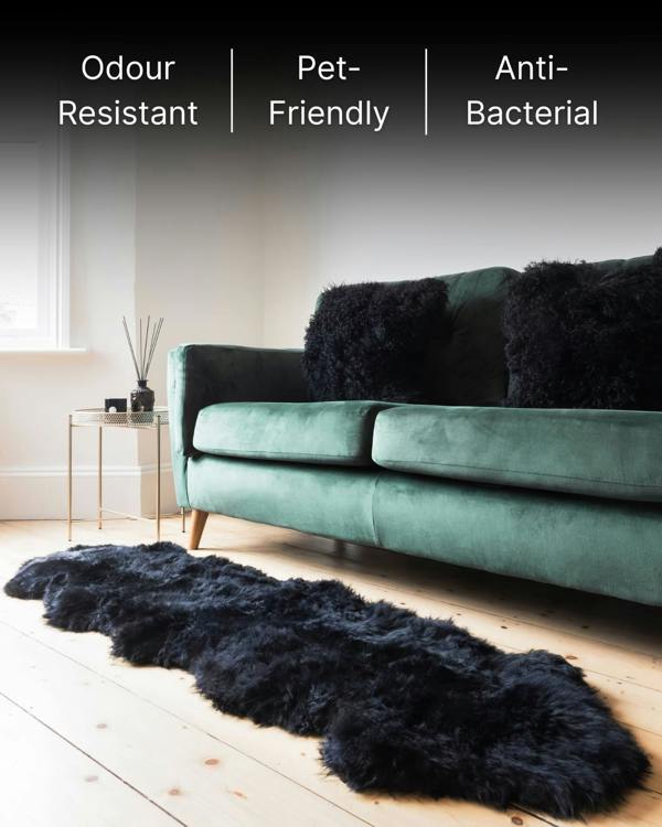 Black mongolian sheepskin pillows on sofa with sheepskin rug.