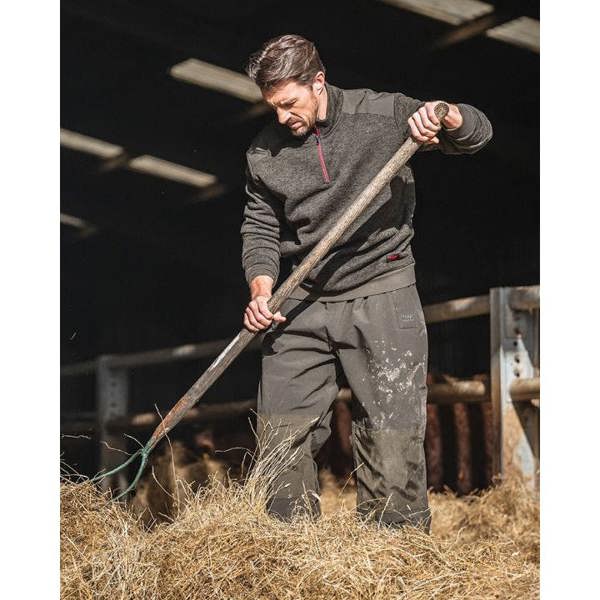 Man wearing a dark green Hoggs of Fife Green King II 1/4 Zip knit whilst moving hay