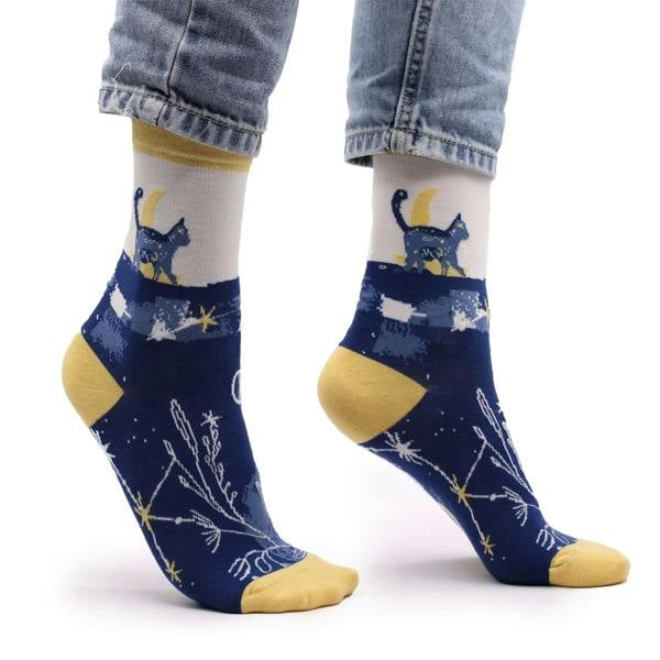 Bamboo socks close-up on feet; navy with yellow cuffs and midnight cat star print.