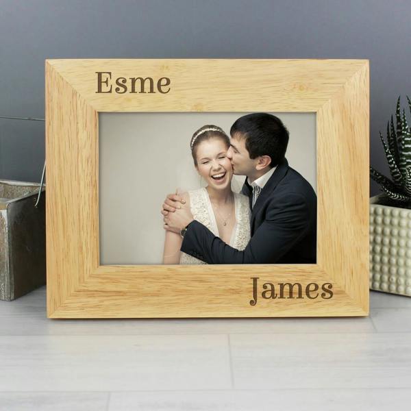 An engraved oak wood photo frame custom etched with the names Esme and James, holding a wedding photo of a couple.