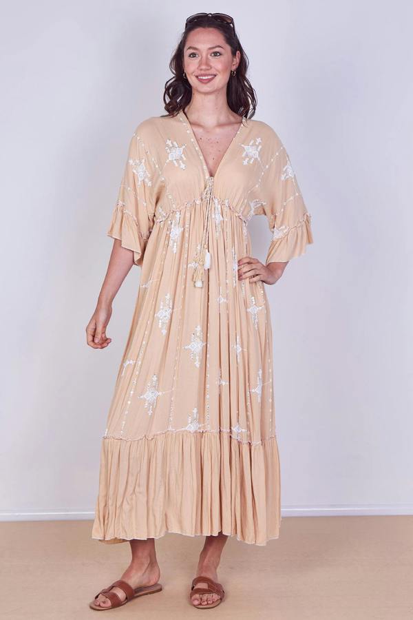 Woman wearing a beige floral dress against a white background