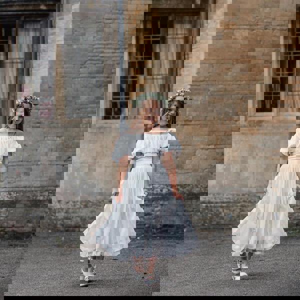 Young girl in a white dress standing in front of a stone building