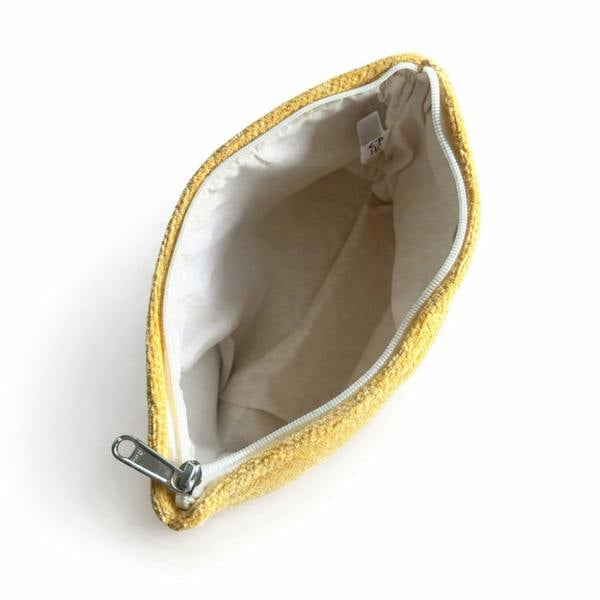 Mustard yellow toiletry bag opened to show beige lining and metal zipper hardware