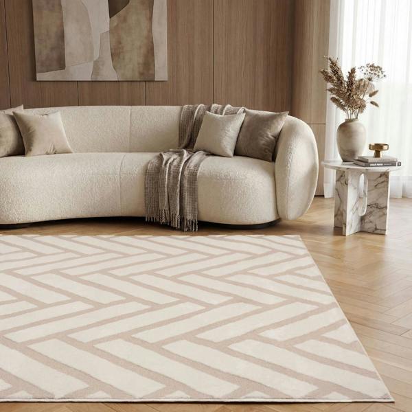 Modern living room with a beige sofa, patterned rug, and abstract art on the wall.
