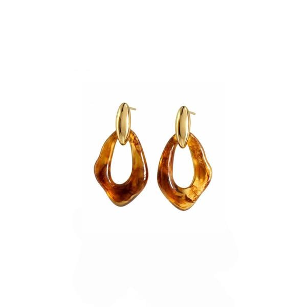 A pair of gold hoop earrings with irregular, organic amber-brown dangling charms, shown on a plain white background.