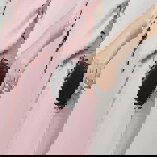 Person wearing a pink coat with a black pocket detail on a plain background