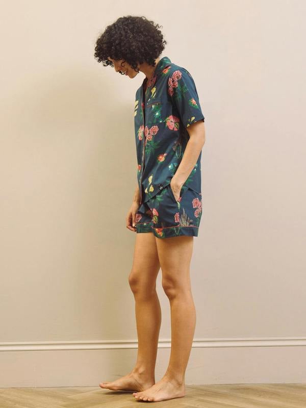 Woman wearing a navy floral short pyjama set against a plain background
