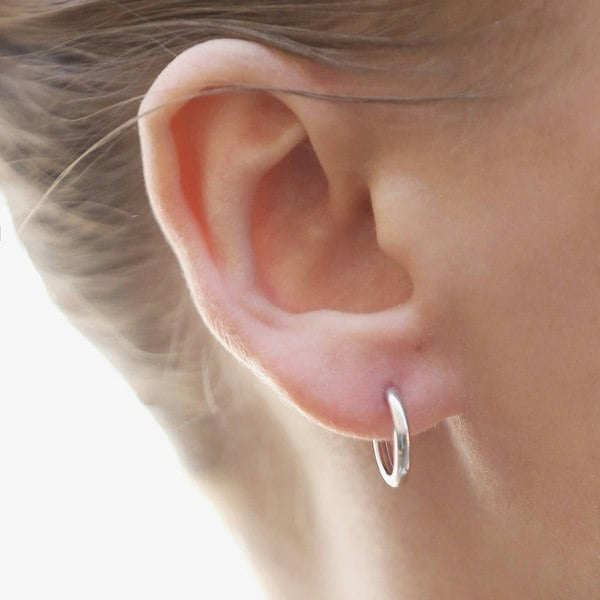 Silver hoop earrings showcased on an ear.