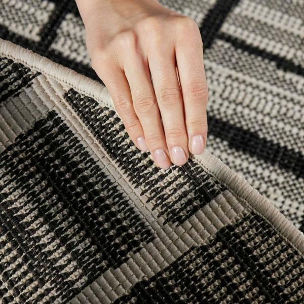 Hand touching a textured black and gray patterned rug