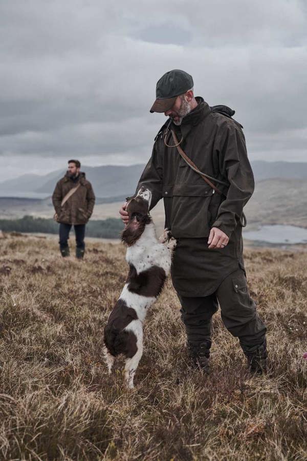 Man training dog on Highland hills wearing hoggs of fife struther trilaminate long smock for weather protection