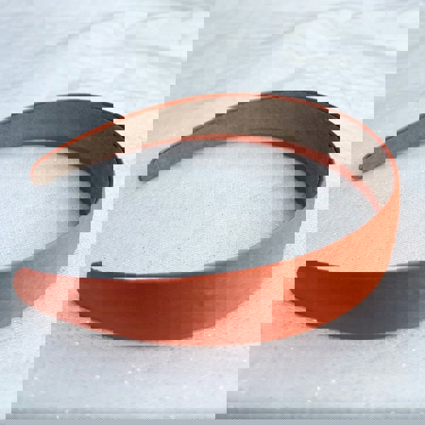 Orange hairband, smooth satin finish, vibrant bold orange shade, padded structure, sleek minimalist design, versatile everyday accessory
