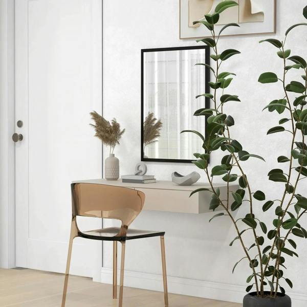 Rectangular black wall mirror above white sink with plant beside the vanity