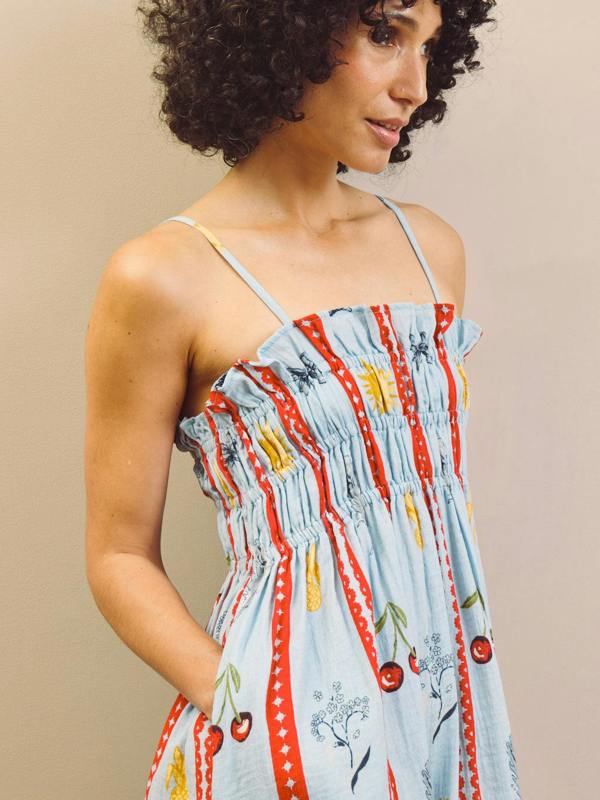 Woman wearing a colourful nightdress with a pattern of cherries and leaves on a beige background