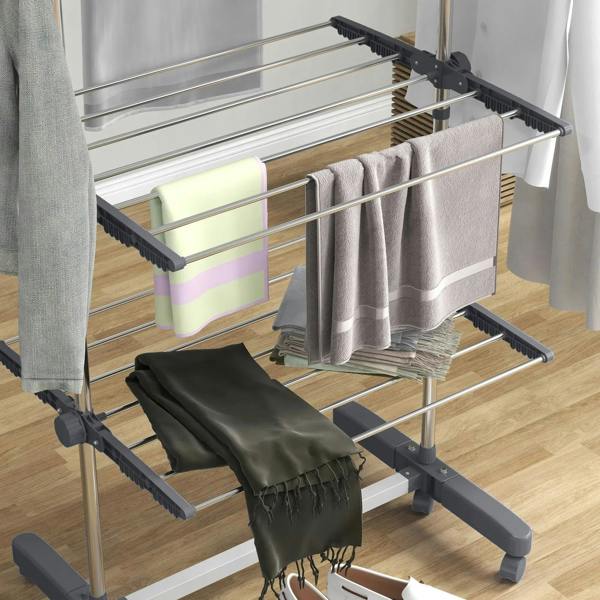 Grey four-tier drying rack loaded with towels and folded clothes on wire shelves